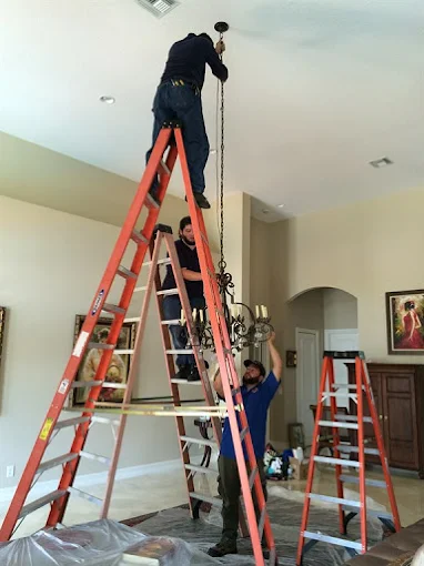 Professional electricians installing ceiling fixture